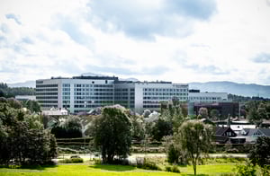 Utsikt mot Nye Stavanger Universitetssjukehus omgitt av trær, boliger og fjell i bakgrunnen.